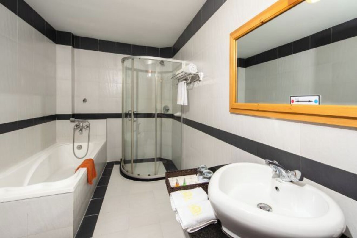 Un baño moderno con ducha envuelta en vidrio, una bañera blanca y un lavabo con espejo superior.