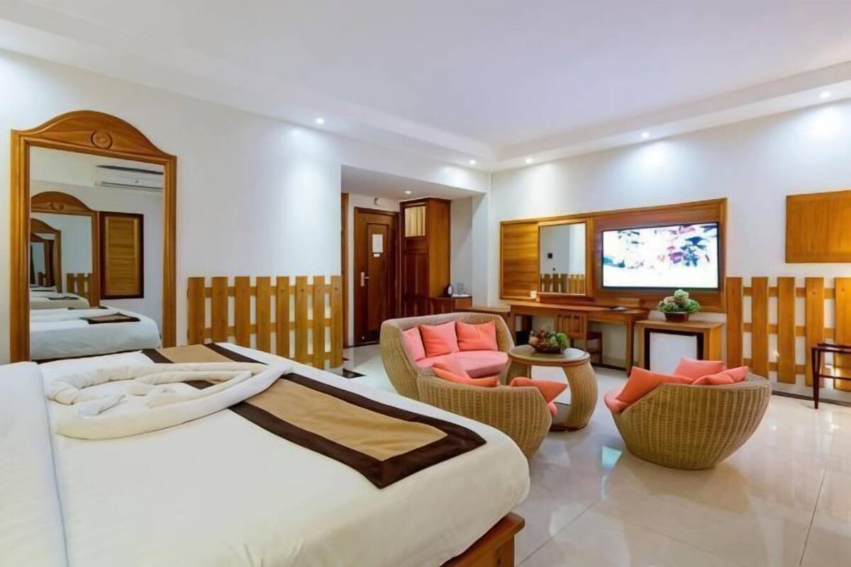 Une chambre d’hôtel équipée d’un lit, d’une télévision, d’un bureau et de meubles en osier.