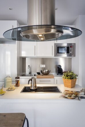 A modern kitchen with a stainless steel range hood, a microwave, a coffee maker, and a wooden cutting board. - Genteel Home Albareda II (Sevilla)