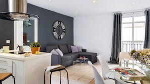 Ein modernes Wohnzimmer mit einem grauen Sofa, einem Couchtisch und einem Essbereich mit einem Glastisch.