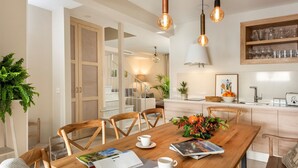 Una cocina moderna con armarios de madera, una mesa de comedor con sillas e iluminación colgante.