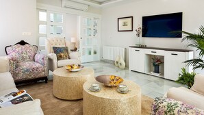 Un salon moderne comprenant un canapé, un fauteuil et une table basse, ainsi qu’une télévision et un meuble décoratif.