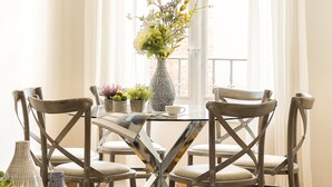 A dining area with a round table, four chairs, a hanging light fixture, and a window with curtains. - Genteel Home Tomas Heredia (Malaga)