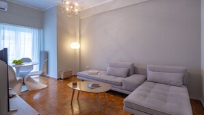A modern living room with a sofa, a coffee table, and a dining area with chairs and a table. - Artemis Deluxe Athens City Center Apartment (Athens)