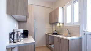 A compact kitchen with wooden cabinets, a countertop, a sink, and a window. - Artemis Deluxe Athens City Center Apartment (Athens)