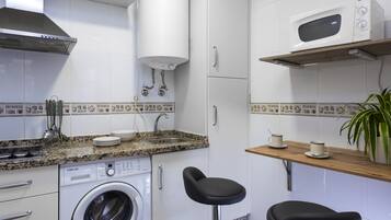 Een koelkast, een magnetron, een koffiezetapparaat/waterkoker, eettafels