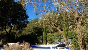 A pool area with lounge chairs and a stone wall.
