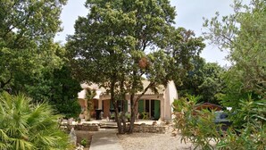 A rustic villa with a gravel pathway leading to a covered patio area.
