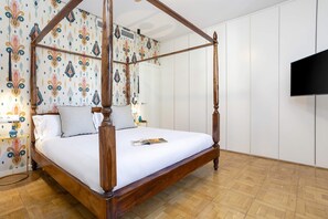 Un lit à baldaquin avec un matelas blanc, une tête de lit en bois et un papier peint à motifs.