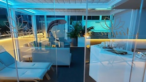 Een moderne, overdekte loungeruimte met glazen scheidingswanden, zithoeken en een receptiebalie.
