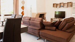 A modern living room with a brown sofa, a flat-screen TV, and a fireplace. - Glyfada Center - Aries Newly Modern Home (Glyfada)