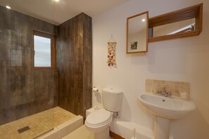 Une salle de bain équipée d’une douche, de toilettes, d’un lavabo et d’un miroir.