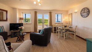 Ein Wohnzimmer mit Fernseher, Sofa und Essbereich mit Stühlen und einem Tisch.