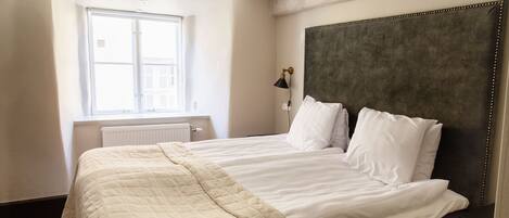 A neatly made bed with a quilted blanket, a dark headboard, and a bedside lamp.