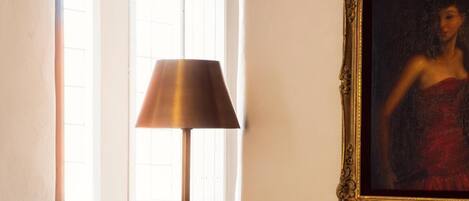 A room with a black leather armchair, a floor lamp, and a framed painting on the wall.