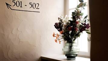 A wall with a directional arrow and numbers '501-502' indicating room numbers. A vase with flowers is placed on a windowsill.