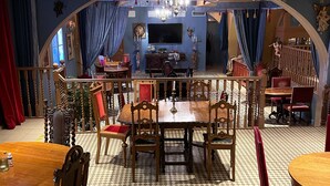 A dining area with a large wooden table and chairs, a chandelier, and a disco ball. - Hotell Visby Börs (Visby)