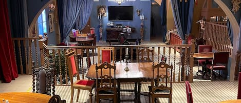 A dining area with a large wooden table and chairs, a chandelier, and a disco ball.
