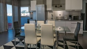 A modern kitchen with a dining area, featuring a glass table, four chairs, and a view of the city through the window. - Virgo Loft  Spectacular Acropolis View (Athens)