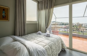Habitación de hotel con cama, ventana con cortinas y vista a la ciudad.