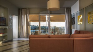 A modern living room with a sectional sofa, a television, and a large window with curtains. - Virgo Loft  Spectacular Acropolis View (Athens)
