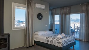 A bedroom with a bed, a window with a view of a cityscape, and a balcony with a table and chairs. - Virgo Loft  Spectacular Acropolis View (Athens)