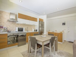 Apartamento, 3 quartos | Cozinha americana privada | Geladeira grande, micro-ondas, fogão, cooktop