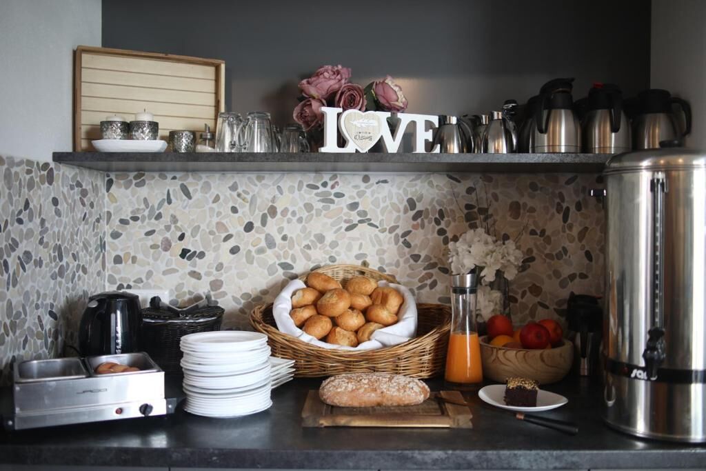 A kitchen counter with a coffee maker, a toaster, a basket of pastries, a loaf of bread, and a sign that reads 'LOVE'.