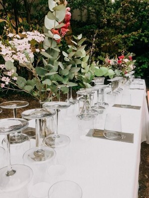 A long table set with wine glasses and plates, surrounded by greenery and flowers. - Wasem Weinhotel (Ingelheim am Rhein)