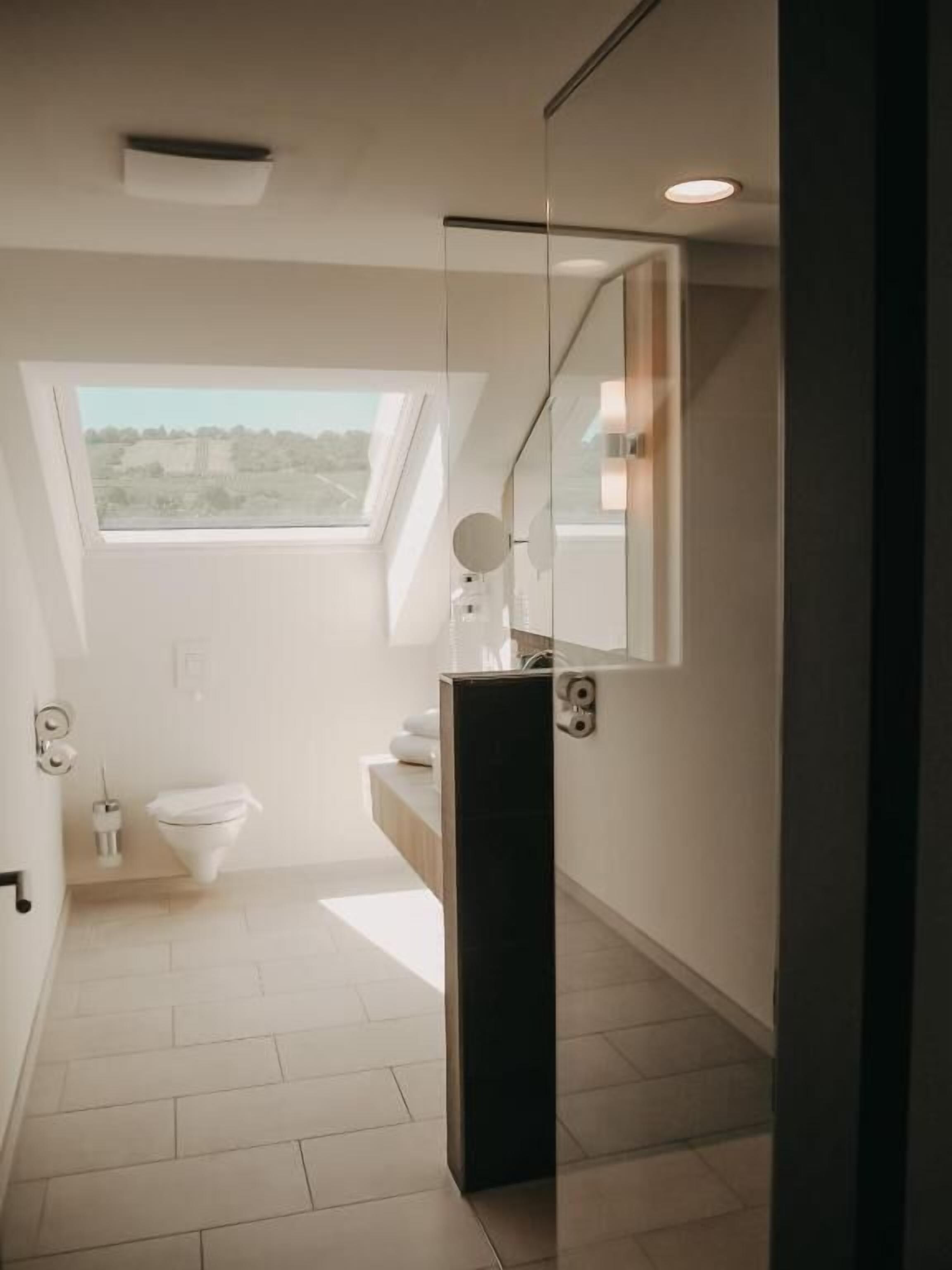 Ein modernes Badezimmer mit Oberlicht, Spiegel und Toilette.
