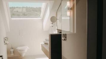 Ein modernes Badezimmer mit Oberlicht, Spiegel und Toilette.