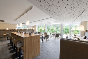 A modern kitchen with a wooden island, bar stools, and pendant lighting.