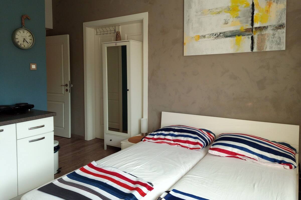 A bedroom with a bed, a dresser, a mirror, and a wall clock.