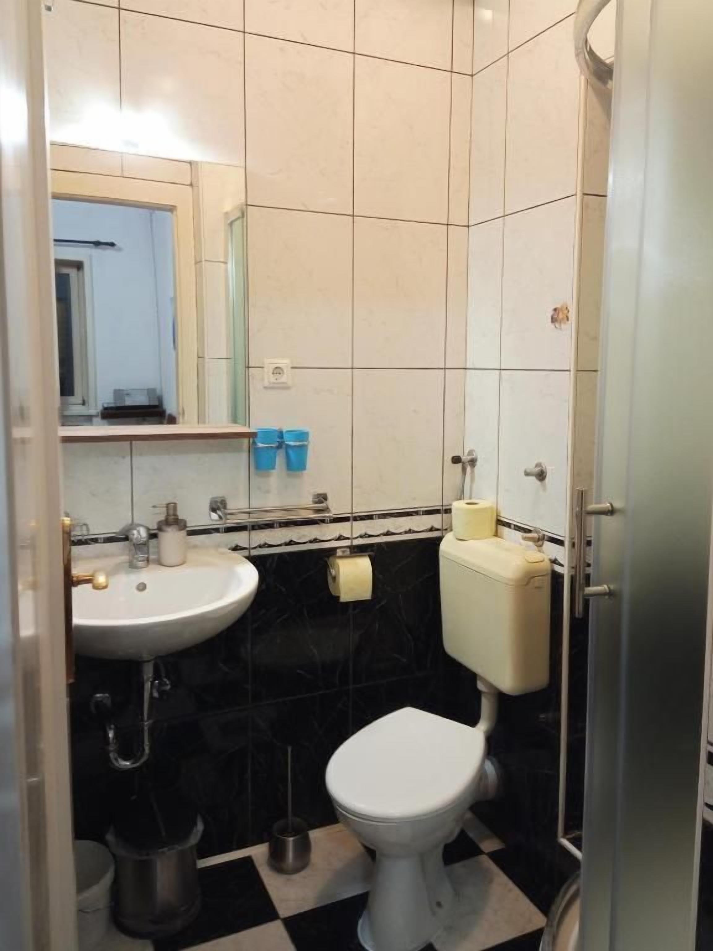 A bathroom with a white sink, toilet, and bidet. There is a mirror above the sink and a towel rack.