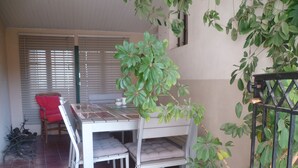 A dining area with a white table and chairs, a red chair, and a potted plant. - Cottage in a 1850 Bastide with infinity pool et counter current swimming system  (Eyguières)