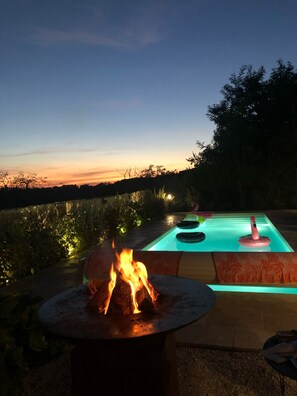 A pool with a fire feature and a view of the sunset.