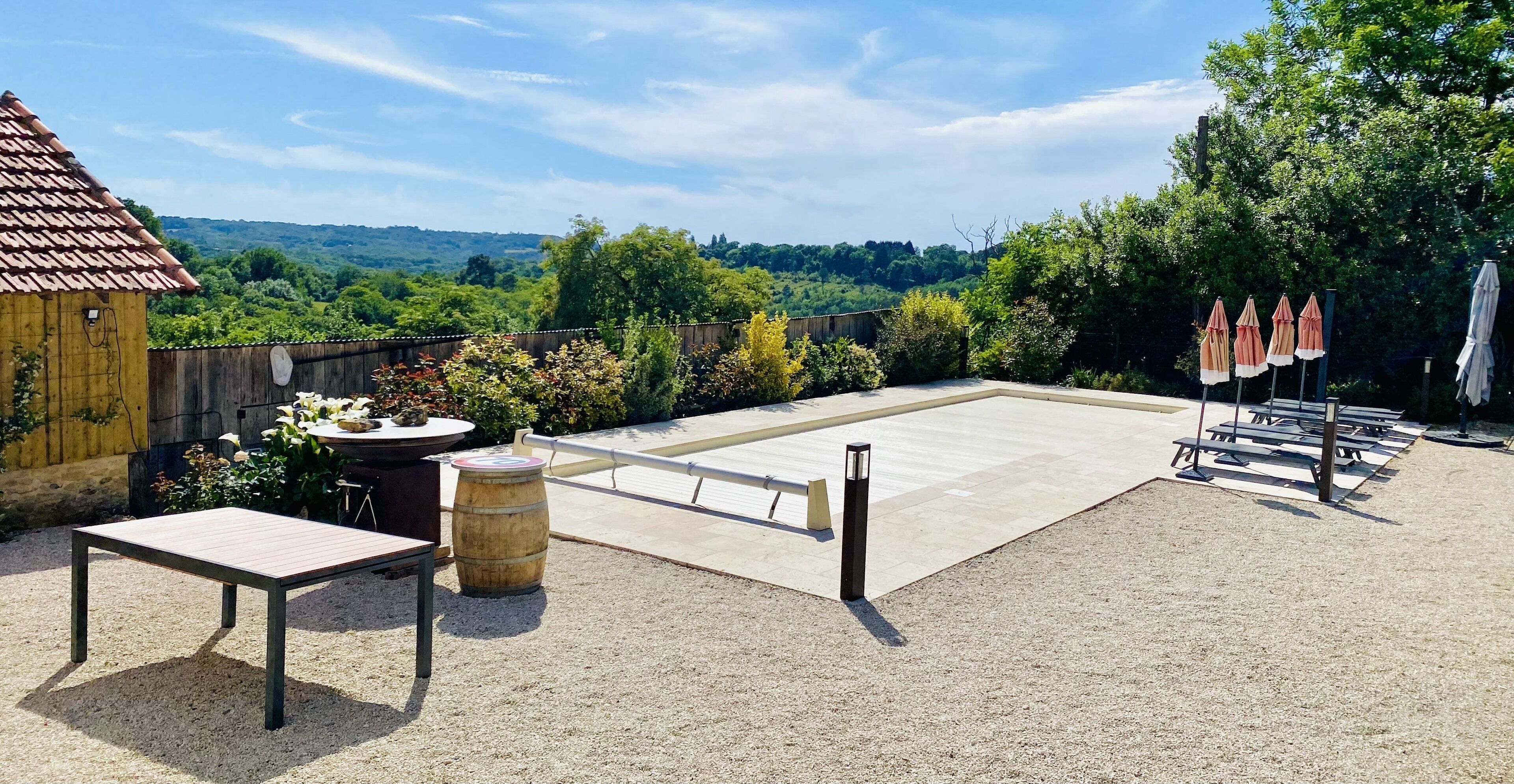 Eine Außenpatio mit einem Tisch, Stühlen und einem Fass.