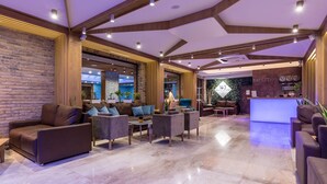 Een moderne lobby met een receptiebalie, een zithoek en een receptiewand.
