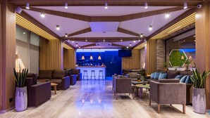 Een moderne lobby met een bar, zitgedeeltes en stadszicht.