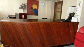Un mostrador de recepción con detalles de madera, un reloj en la pared y un cuadro encima.