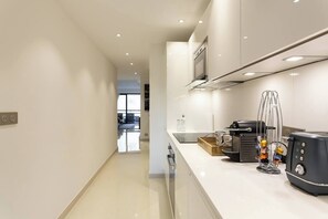 Uma cozinha moderna com cafeteira, chaleira e bule de chá na bancada.