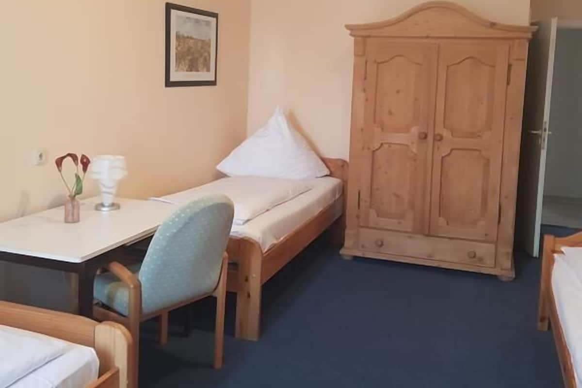 A small, cozy room with a bed, a desk with a chair, and a wardrobe.