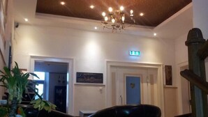 A spacious lobby with a high ceiling, a chandelier, and a staircase. - Pension Im Bett (Nuremberg)