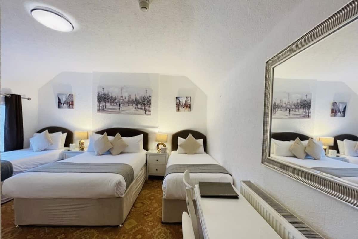 A hotel room with two beds, a large mirror, and wall-mounted artwork.