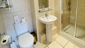 A modern bathroom with a toilet, sink, and glass-enclosed shower. - Fairlight Guesthouse (Penrith)