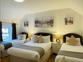 Habitación de hotel con dos camas, una ventana con cortinas y una obra de arte colgada en la pared.