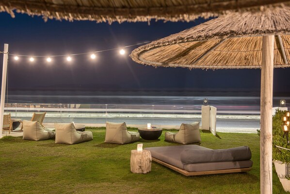 Un espacio de descanso frente a la playa con asientos y un hogar para fuego, con vistas al océano.