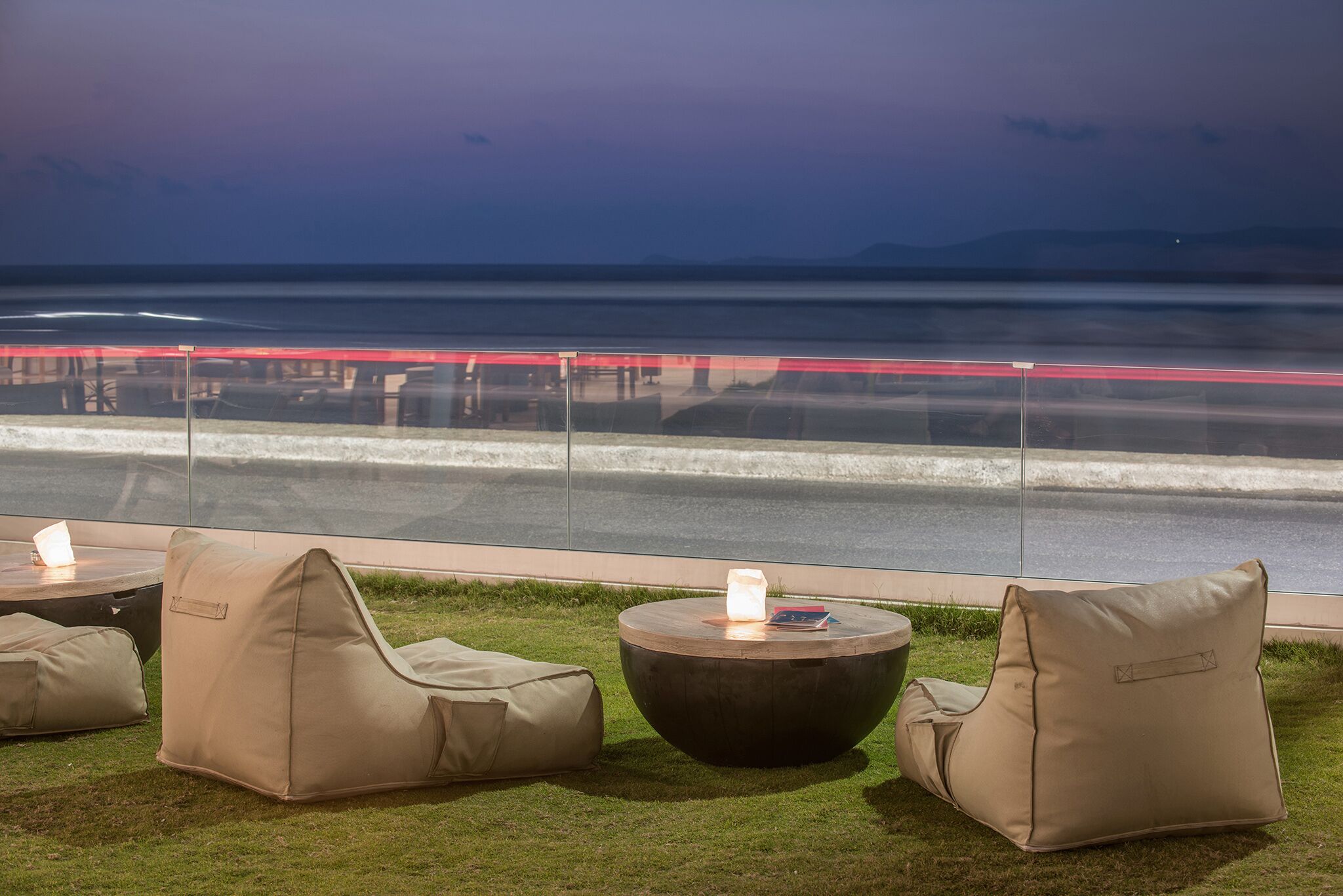 Outdoor seating with a view of the ocean and a bridge.