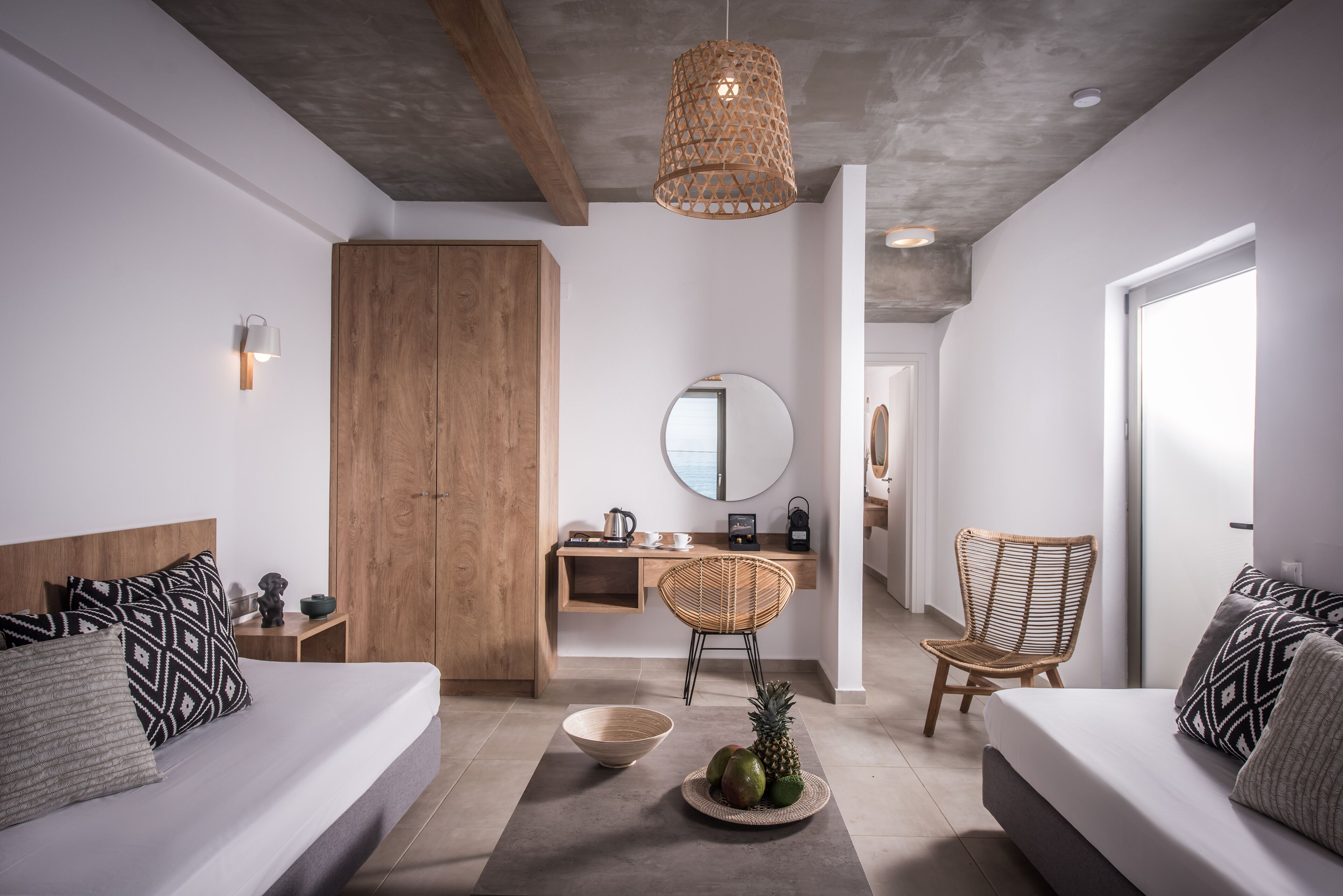 Une chambre d’hôtel moderne avec un grand lit, deux canapés, une armoire en bois, un bureau avec un ordinateur et un coin repas comprenant une chaise et une table.