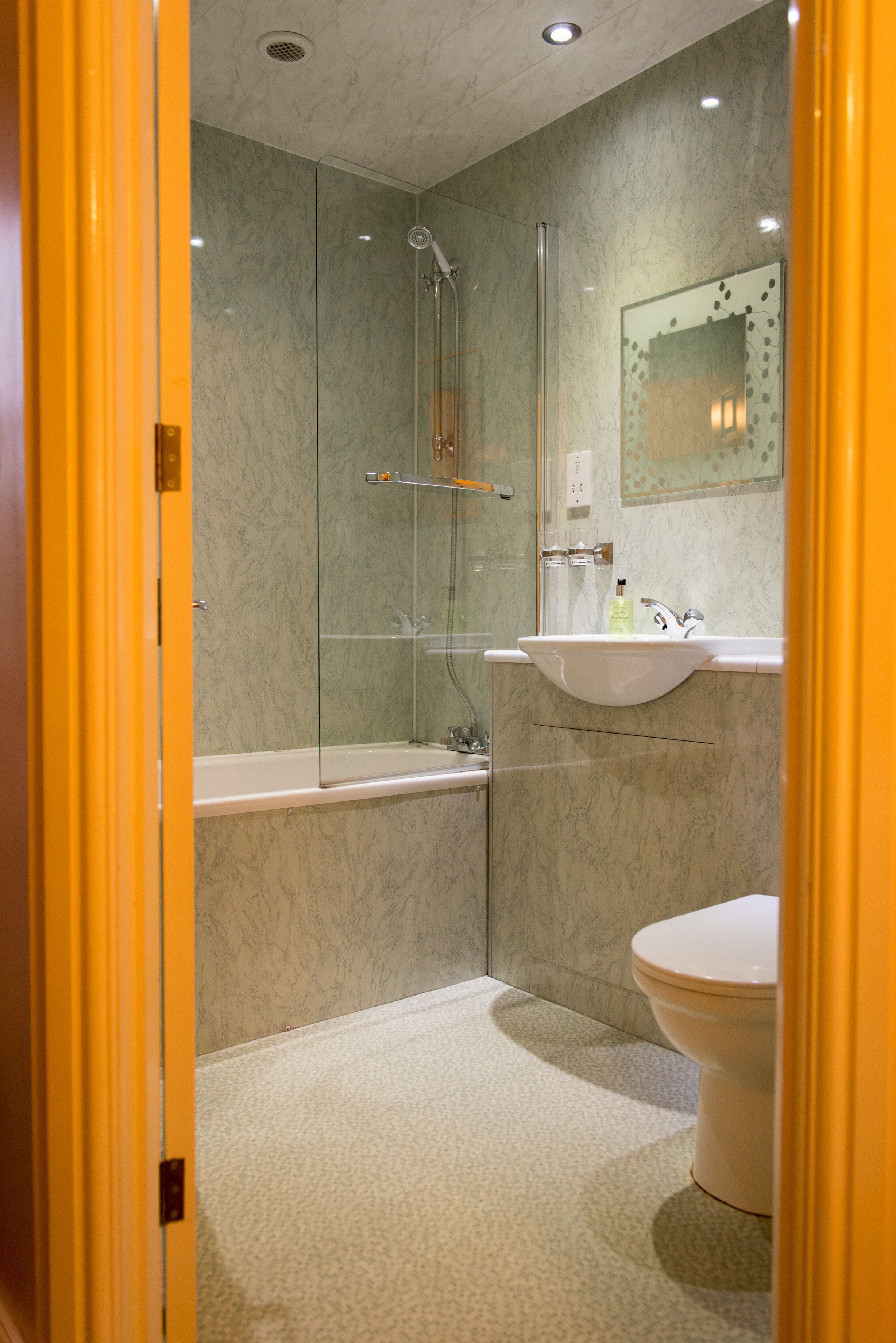 Un baño moderno con ducha de mampara de vidrio, lavamanos blanco y retrete.